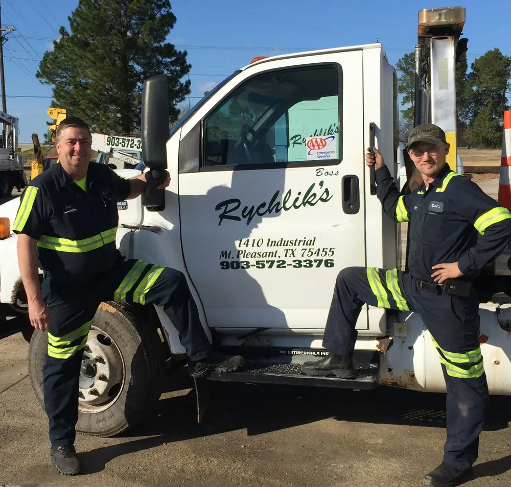 Two uniformed Rychlik's team members with a service truck